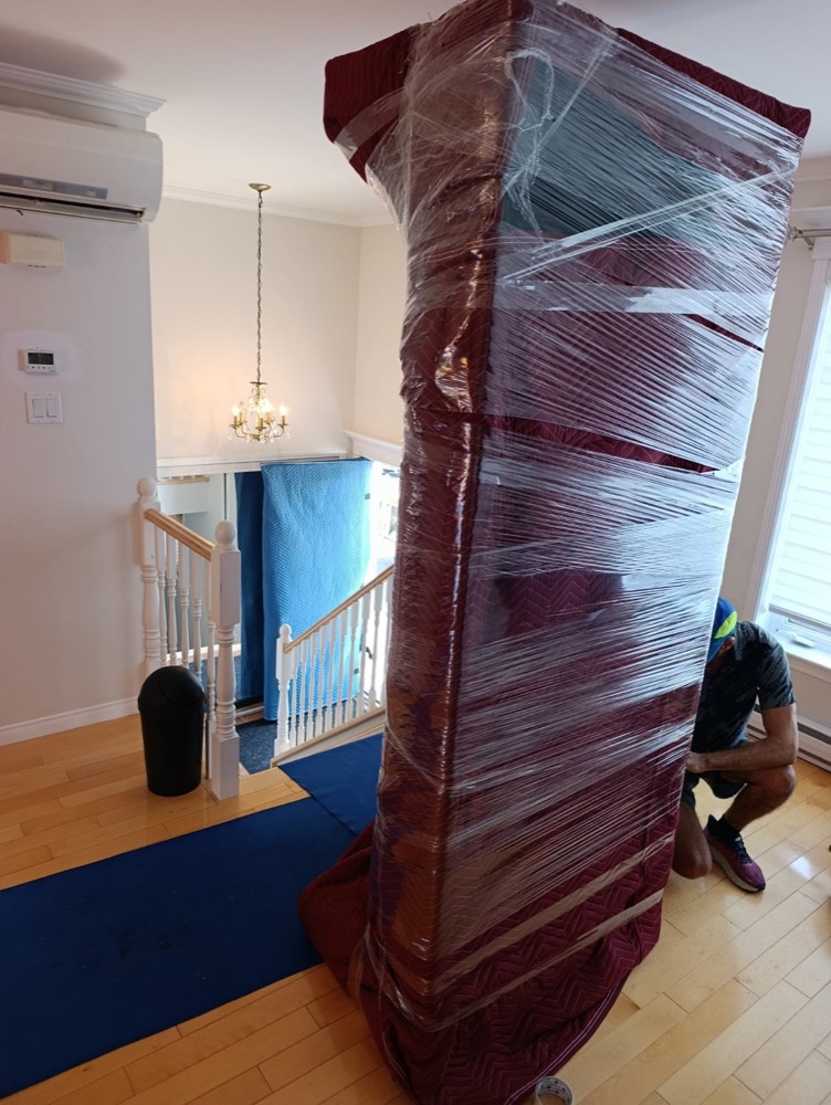 Mobilier enveloppé dans des couvertures de déménagement maintenues par du film étirable