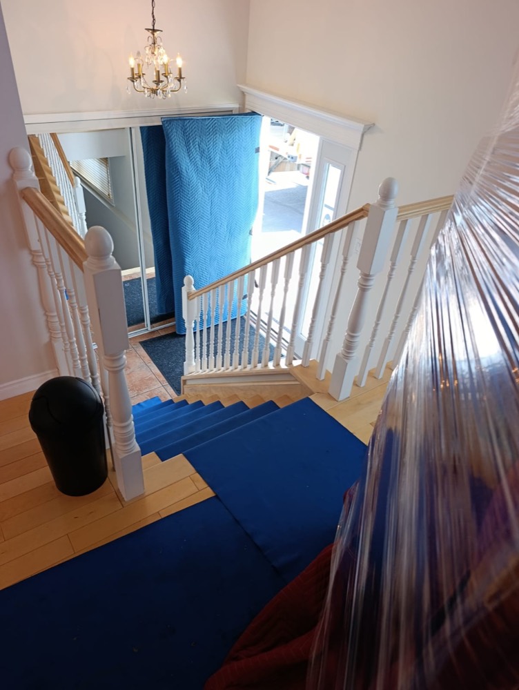 Escalier recouvert de tapis de protection et accès protégé par des couvertures